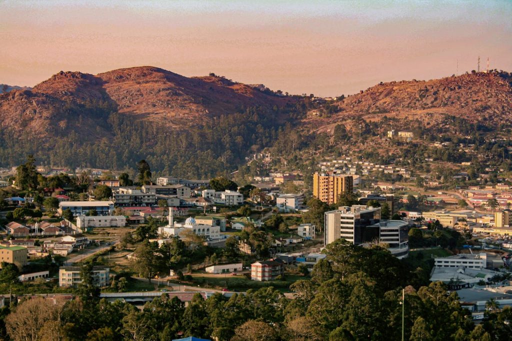 Scenic aerial view of Manzini, Eswatini at sunset with lush hills in the background.